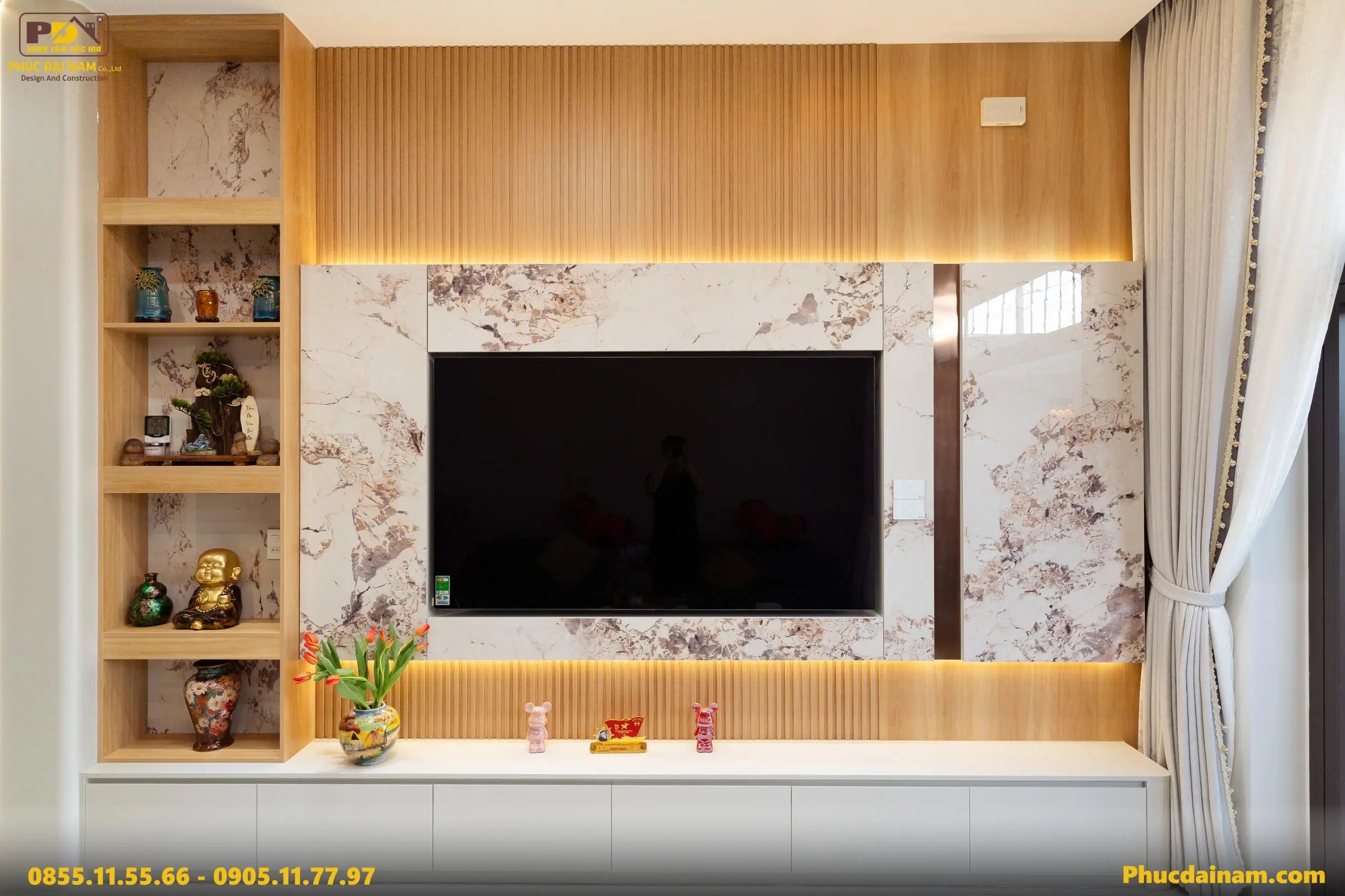 Điểm nhấn là mảng tường tivi được thiết kế đồng bộ với các vật liệu giả đá, lam gỗ và hệ thống đèn hắt